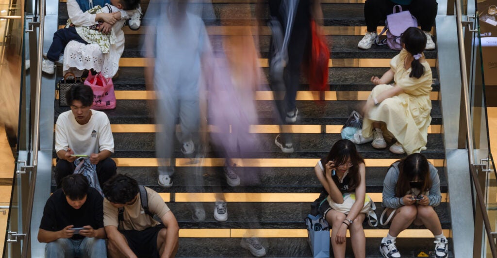 People sit on a staircase as others walk past in Chongqing, China, on May 1.