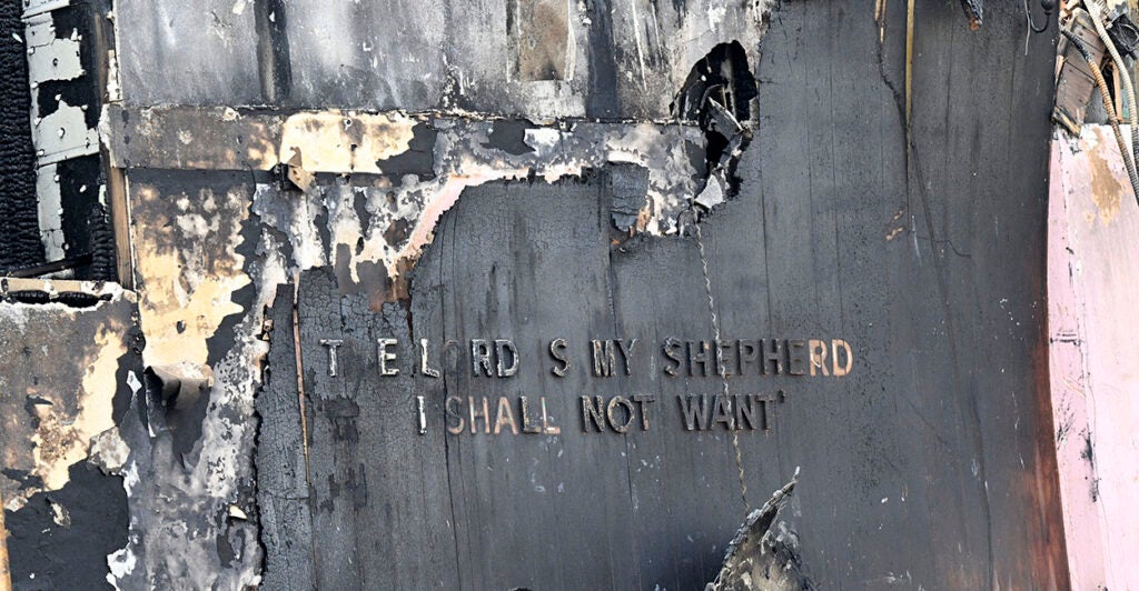 A building destroyed with the words "The Lord Is My Shepherd I Shall Not Want" barely visible