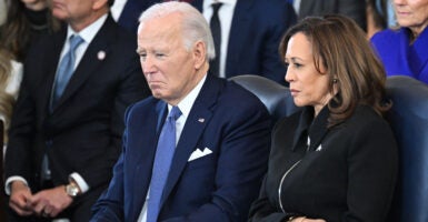 Joe Biden in a dark suit sitting next to Kamala Harris in a black jacket
