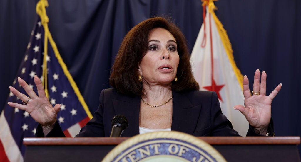 Jeanine Pirro, with her hands raised, stands behind a podium