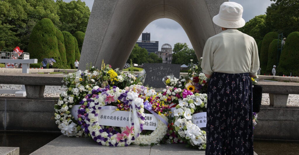 A visitor prays after offering flowers in front of the cenotaph ahead of the 80th anniversary of the atomic bomb dropped on Hiroshima at the Hiroshima Peace Memorial park on August 05, 2025 in Hiroshima, Japan.