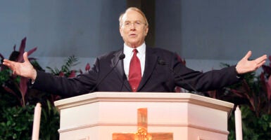 James Dobson behind the pulpit, his arms spread wide.