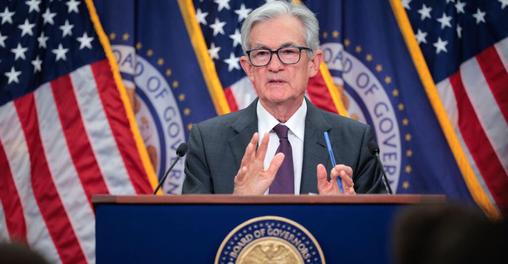 Fed Chairman Jerome Powell speaking at a podium with American flags behind him