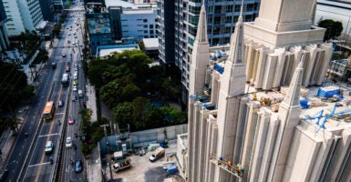 View of cars on street and construction crew while working on temple of the Church of Jesus Christ of Latter-day Saints (LDS)