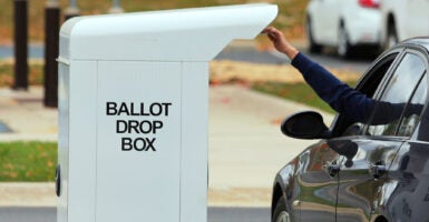 A drive-up voter drops off his election ballot for the 2020 General Election in the drop box outside of the West Bloomfield Township Hall in West Bloomfield, Michigan