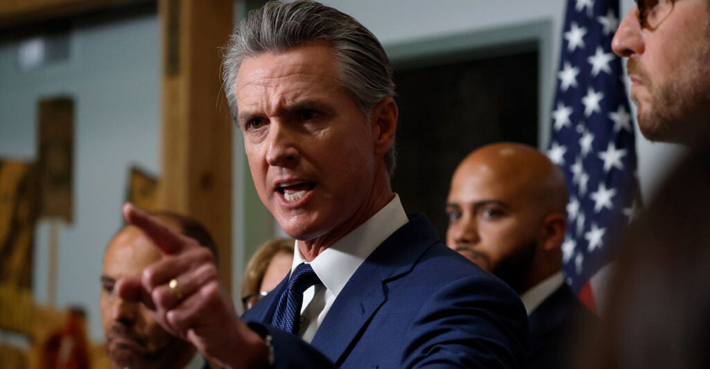 Governor Gavin Newsom in a blue suit and blue tie pointing his finger looking angry