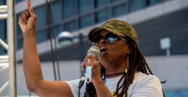 Iris Roley gestures with her finger as she holds a microphone.