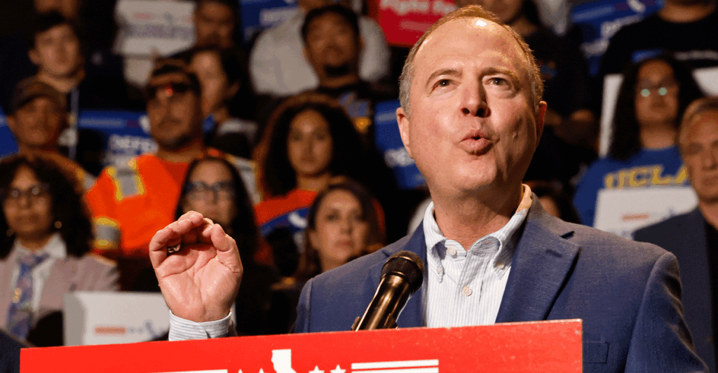 Sen. Adam Schiff speaking at a podium with a crowd in bleachers behind him