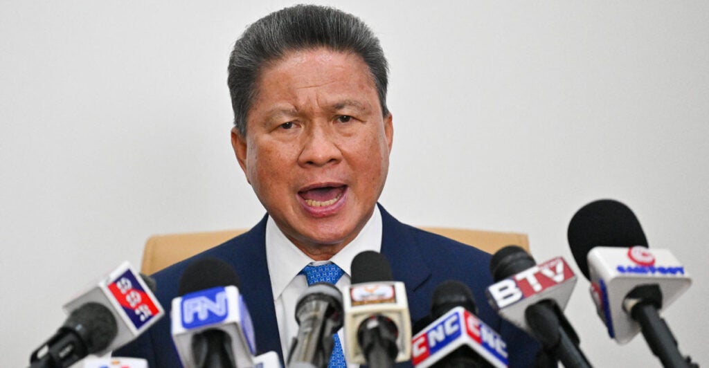 Sun Chanthol, Cambodia's deputy prime minister, speaks during a press conference with multiple microphones facing him.