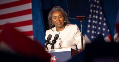 Winsome Earle-Sears in white in front of American flags