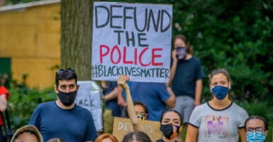 Protesters in masks hold up defund the police, Black lives matter banners