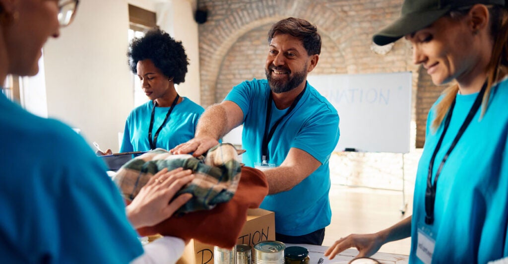 Volunteers in light blue T-shirts hand out food and clothing to the needy