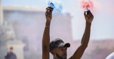 A supporter of gender-affirming care hold colored smoke devices during a rally outside of the Supreme Court in Washington, D.C. on June 20, 2025 in response to the court's ruling upholding Tennessee's ban on gender-affirming care for minors.