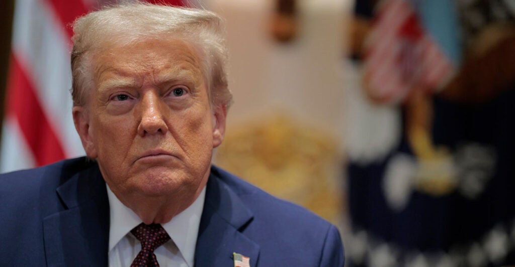 President Donald Trump looks straight ahead with his arms by his side during a cabinet meeting.
