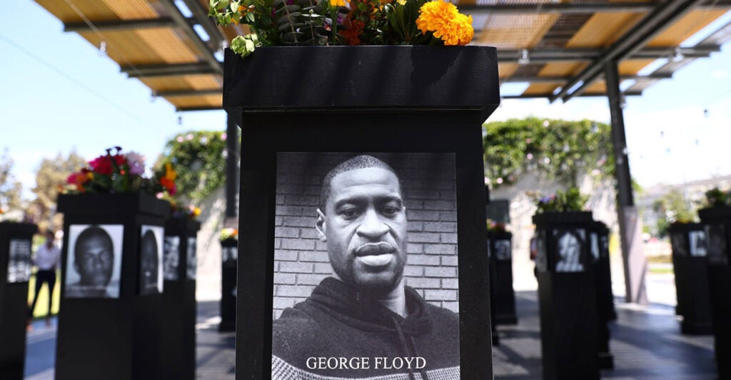 A large photo of George Floyd is on a podium that has flowers on top.