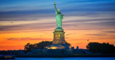 The Statue of Liberty is shown with the sun setting in the background.