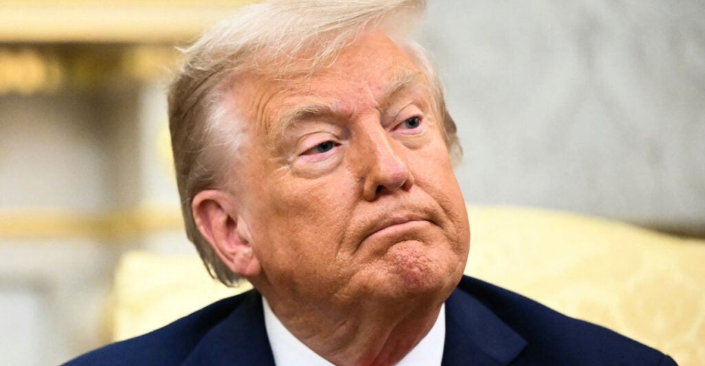 President Donald Trump sits in a yellow chair in the Oval office.