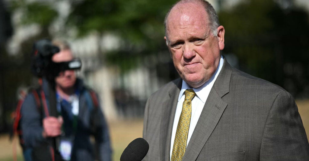 Wearing a gray suit and a gold tie, border czar Tom Homan speaks to the press outside the White House.