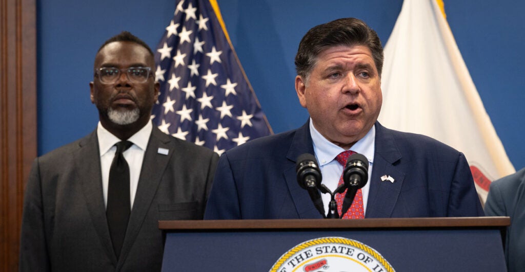Illinois Gov. JB Pritzker speaks to the press as Chicago Mayor Brandon Johnson listens.