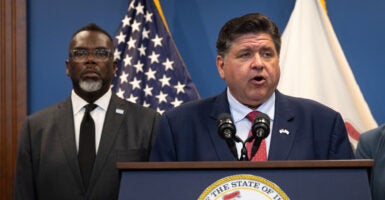 Illinois Gov. JB Pritzker speaks to the press as Chicago Mayor Brandon Johnson listens.