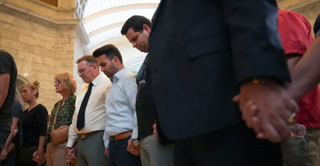 A group of people clutch hands and pray during a prayer vigil for Charlie Kirk.