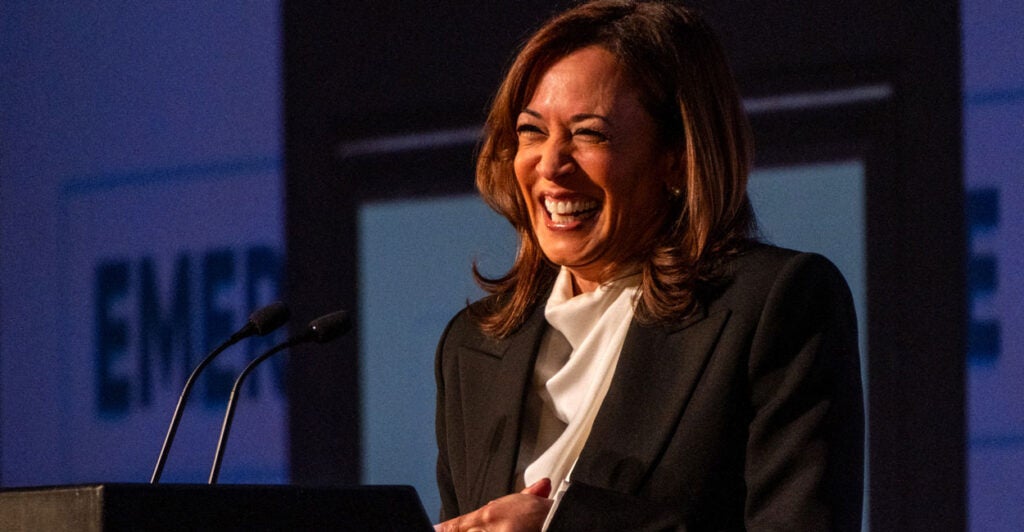 A laughing Kamala Harris in brown jacket and white blouse.