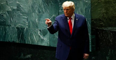 President Donald Trump against green background at U.N., points a finger.