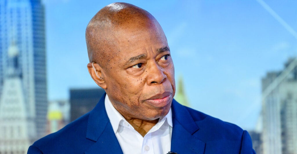 Close-up of Eric Adams in a blue jacket with open-collar white shirt.