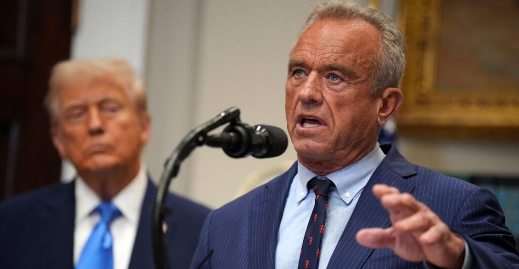 Robert F. Kennedy Jr. speaks into microphone with President Donald Trump looking on.