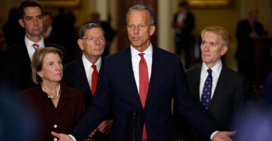 John Thune, arms spread, addresses supporters, surrounded by a group of GOP senators.