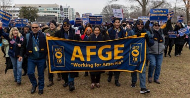Protesters march behind a banner for the American Federation of Government Employees or AFGE.