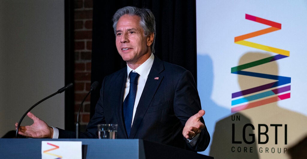 Antony Blinken in front of an LGBTI sign.
