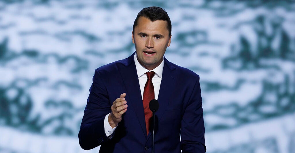 Charlie Kirk gestures in a blue suit