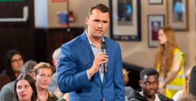 Charlie Kirk holds a microphone in front of students.