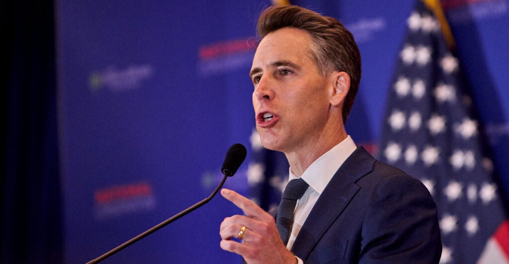 Josh Hawley Speaking on stage with American flag in the background