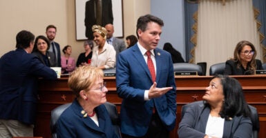 Reps. Marcy Kaptur, Brendan Boyle, and Pramila Jayapal talk amongst themselves in committee during a bill markup.