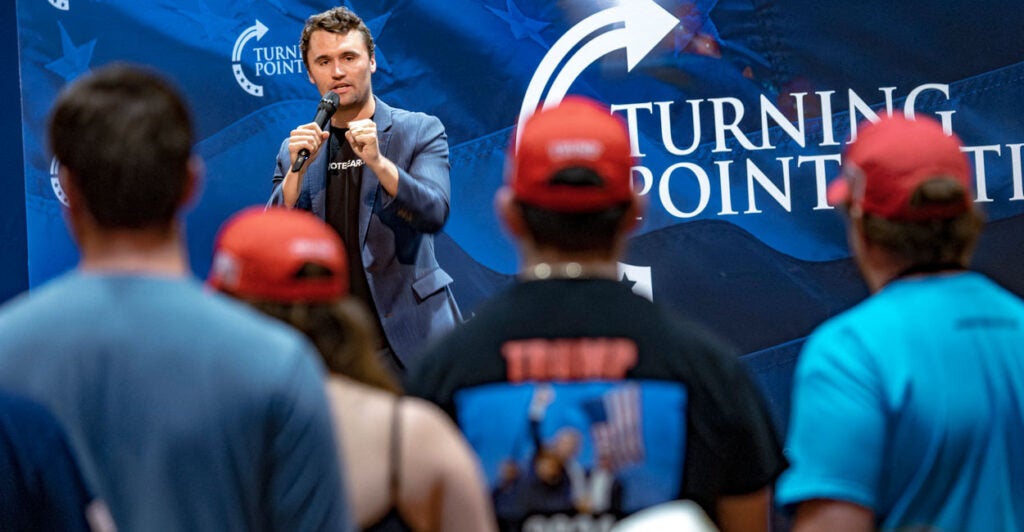 Charlie can on stage speaking to students standing at a turning point event. With the turning point logos in the background