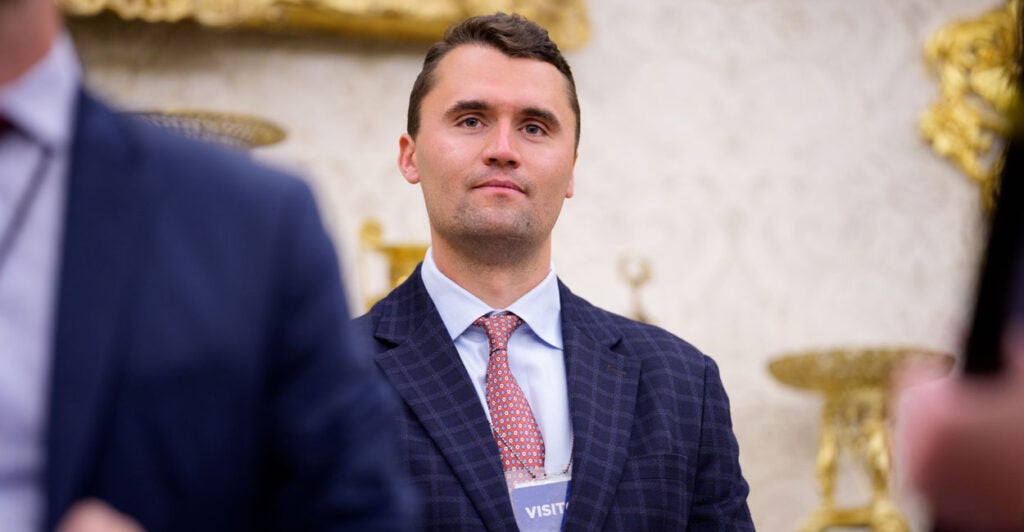 Charlie Kirk smiles while wearing a visitor's badge at the White House.
