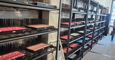 A row of metal racks containing electronic equipment for a server farm.
