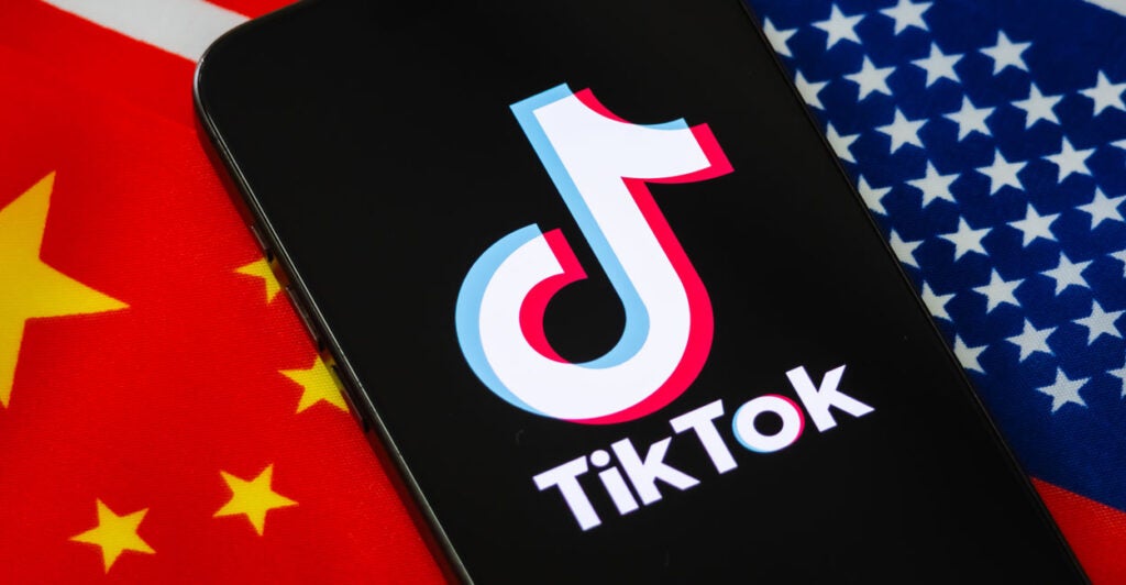 In this photo illustration, a smartphone displays the logo of TikTok with the national flags of China and the United States shown in the background.