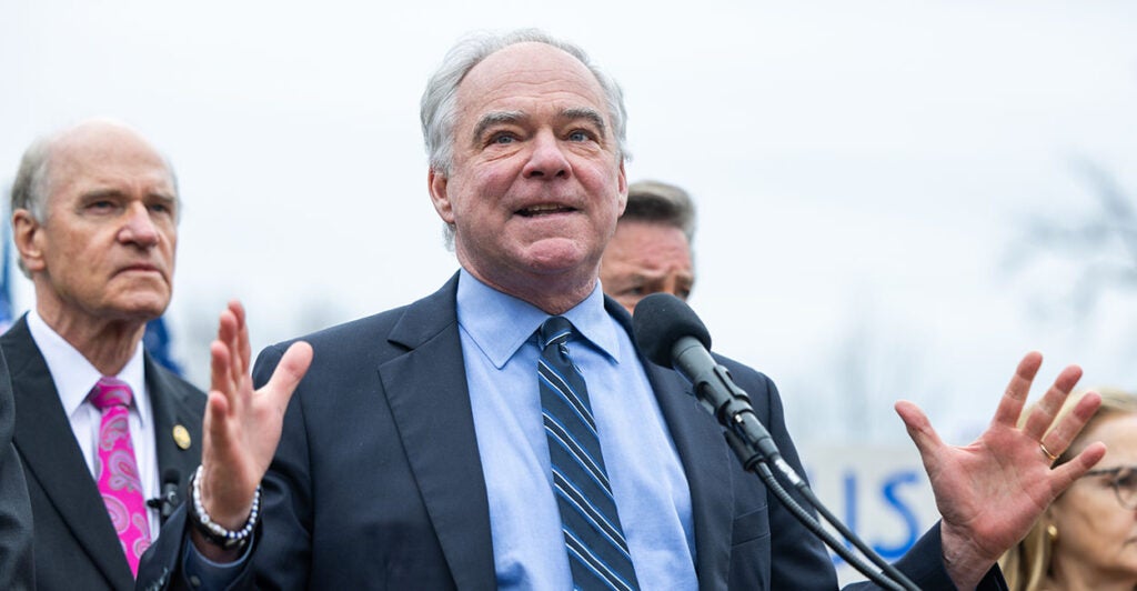 Tim Kaine in a blue suit gestures wildly