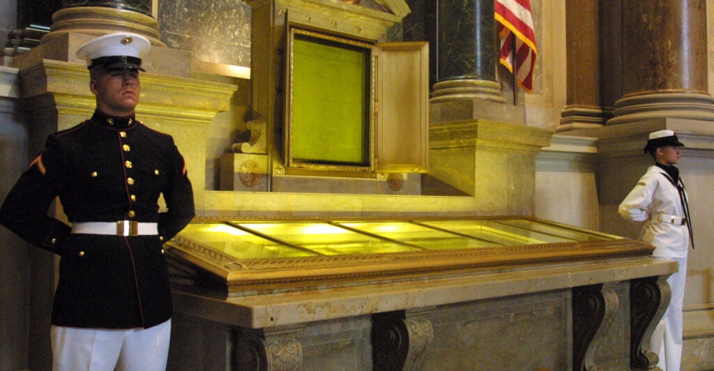 An honor guard stands next to the original copies of the Declaration of Independence, the Constitution and the Bill of Rights July 4, 2001 at the National Archives in Washington, D. C.