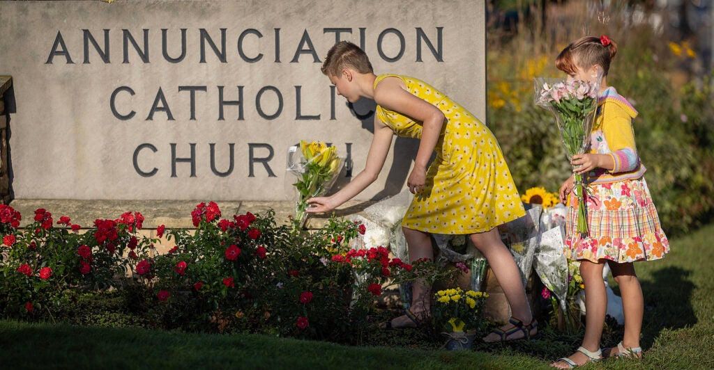 Ruth Pierluissi, 11, left, and Sage Pierluissi, 8, bring flowers to lay in front of Annunciation Catholic Church in Minneapolis, Minn., on Thursday, August 28, 2025.