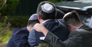 Four people form a circle as they hug each other in grief after their house of worship was attacked.