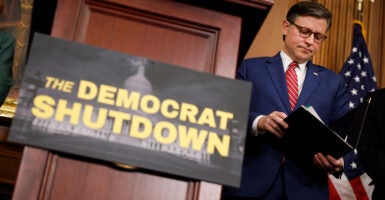 House Speaker Mike Johnson, R-La., attends a news conference at the Capitol on Wednesday about the federal government shutdown, with a sign proclaiming "Democrat Shutdown" hung on the lectern.