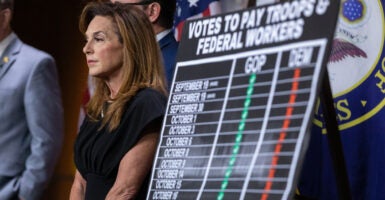 Rep. Lisa McClain, R-Mich., attends a GOP leadership news conference at the Capitol on Oct. 17 on the federal government shutdown. A chart beside her shows a comparison of votes on the issue between Republicans and Democrats.