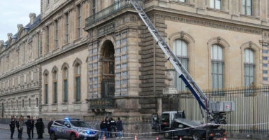 French police officers stand next to a furniture elevator used by robbers to enter the Louvre Museum.