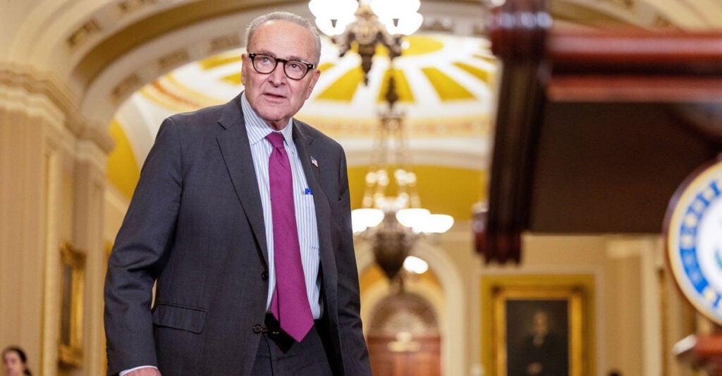 Chuck Schumer stands in the hallway of the U.S. Capitol while looking to his left.