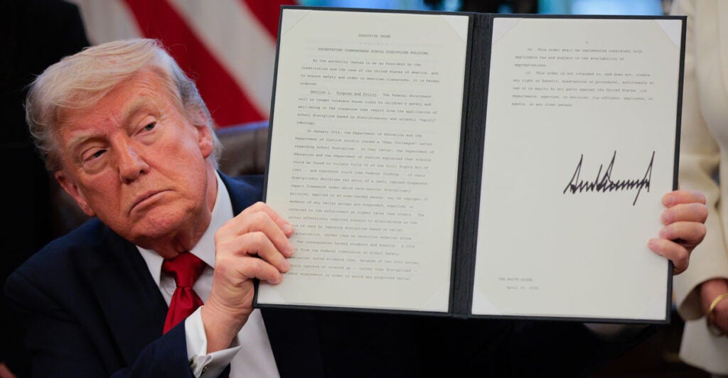 Donald Trump holding up a signed executive order.