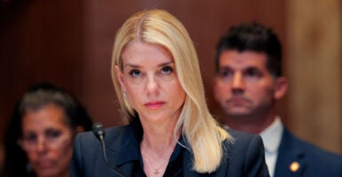 Pam Bondi in black suit stares into the camera during a congressional hearing.